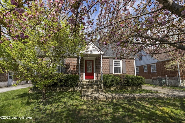 view of front of house featuring a front yard, fence, and brick siding