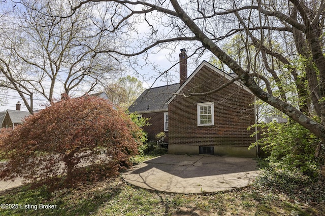 view of side of home featuring a patio, a chimney, and brick siding