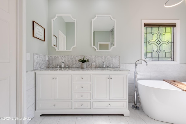 full bathroom featuring a soaking tub, double vanity, a sink, and tile patterned floors