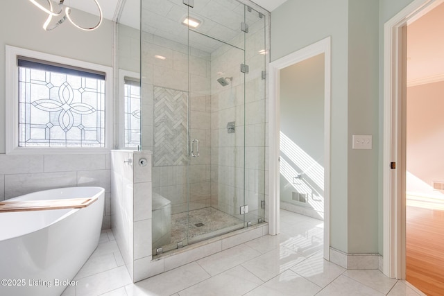 bathroom with a stall shower, a freestanding tub, tile walls, and tile patterned floors