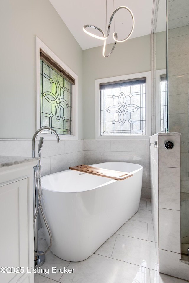 full bath with a freestanding bath, tile walls, and tile patterned floors