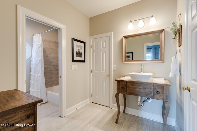 full bathroom featuring baseboards, shower / bath combo with shower curtain, and a sink