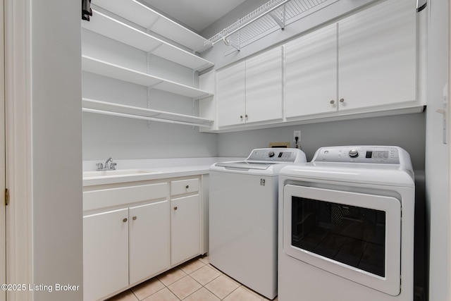 laundry area featuring light tile patterned floors, washing machine and dryer, cabinet space, and a sink