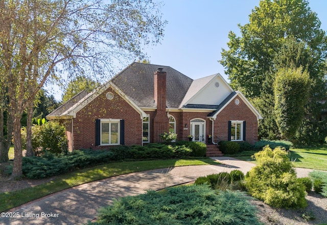 view of front of house with a shingled roof, brick siding, and a chimney