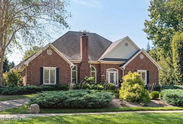 view of front of home with brick siding, a chimney, and roof with shingles