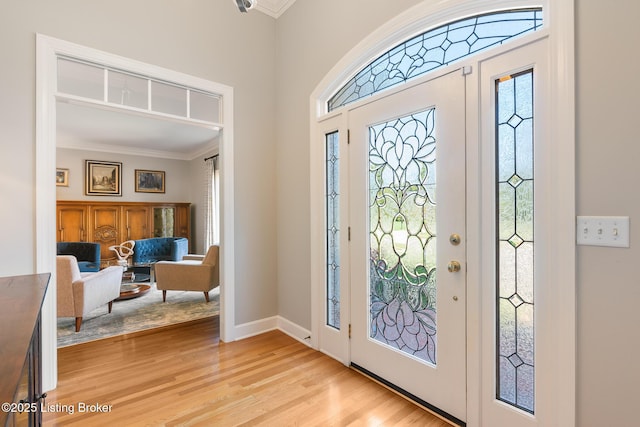 entrance foyer with light wood-style floors, baseboards, and crown molding