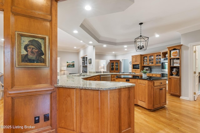 kitchen featuring brown cabinets, stainless steel appliances, light wood-style flooring, glass insert cabinets, and a sink