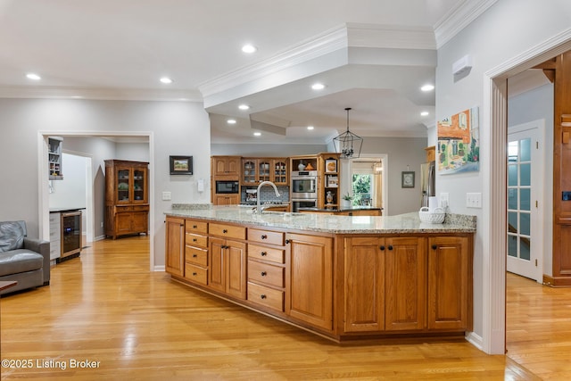 kitchen with light stone counters, wine cooler, light wood finished floors, a sink, and a peninsula