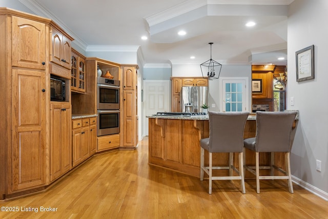 kitchen featuring light wood-style flooring, a breakfast bar area, ornamental molding, a peninsula, and stainless steel appliances