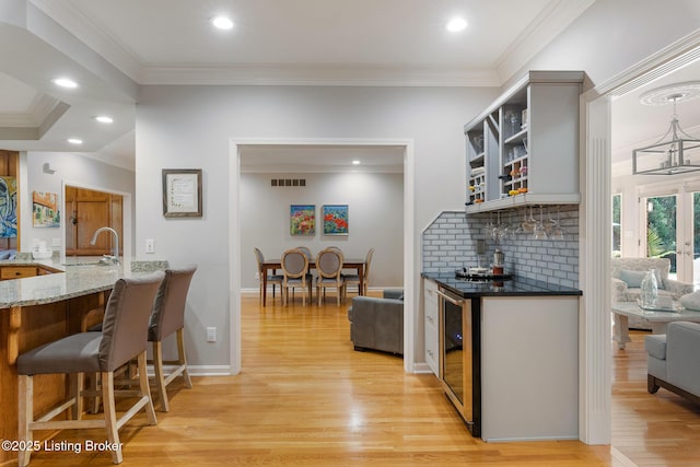 kitchen featuring wine cooler, visible vents, a sink, and ornamental molding