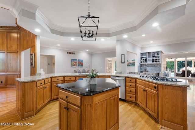 kitchen with a raised ceiling, open floor plan, a center island, stainless steel appliances, and a sink