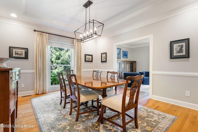 dining area featuring baseboards, crown molding, and light wood finished floors