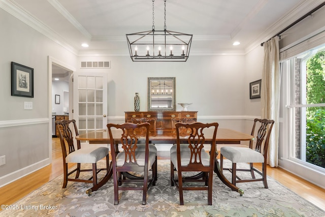 dining area featuring crown molding, visible vents, baseboards, light wood-type flooring, and an inviting chandelier