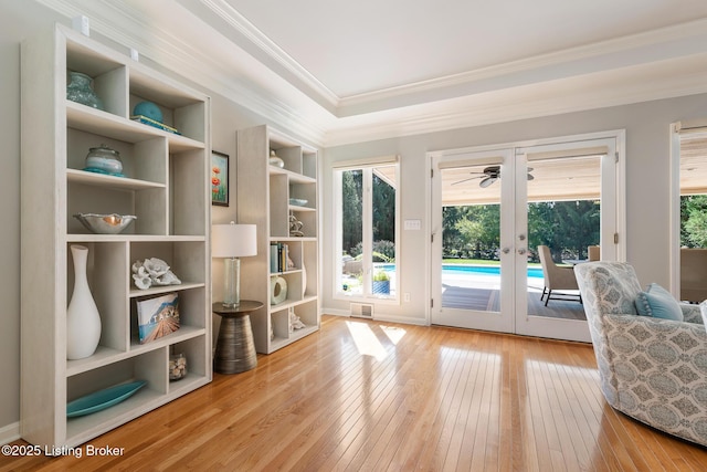 sitting room with hardwood / wood-style flooring, ornamental molding, built in features, and french doors