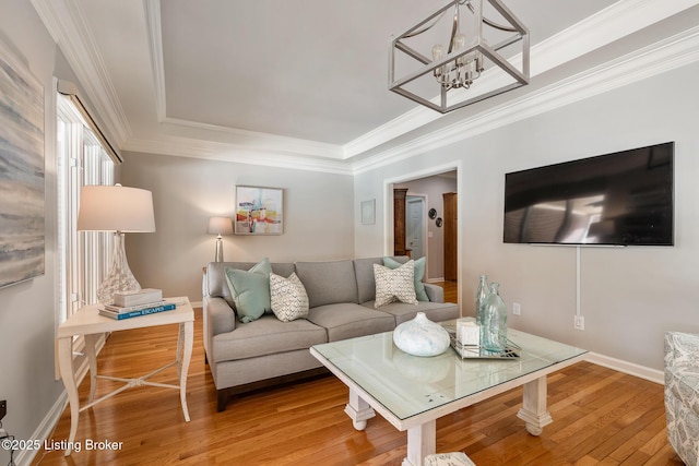 living room with ornamental molding, wood finished floors, and baseboards