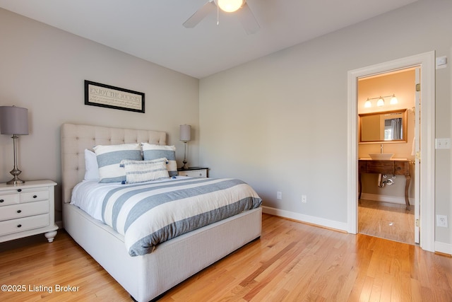 bedroom featuring ensuite bathroom, ceiling fan, light wood-type flooring, and baseboards