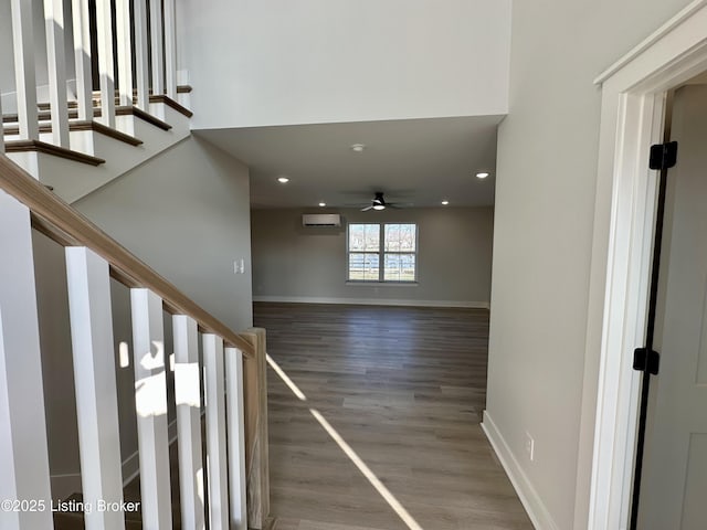 stairs featuring baseboards, a ceiling fan, wood finished floors, an AC wall unit, and recessed lighting