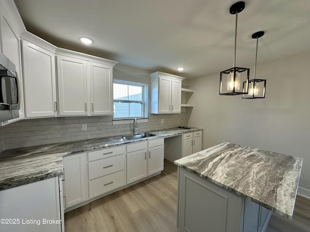 kitchen with white cabinets, decorative backsplash, light wood-type flooring, open shelves, and a sink