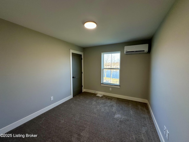 spare room with an AC wall unit, visible vents, dark carpet, and baseboards