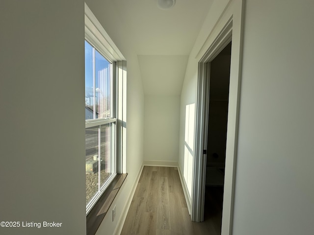 corridor with lofted ceiling, baseboards, and wood finished floors