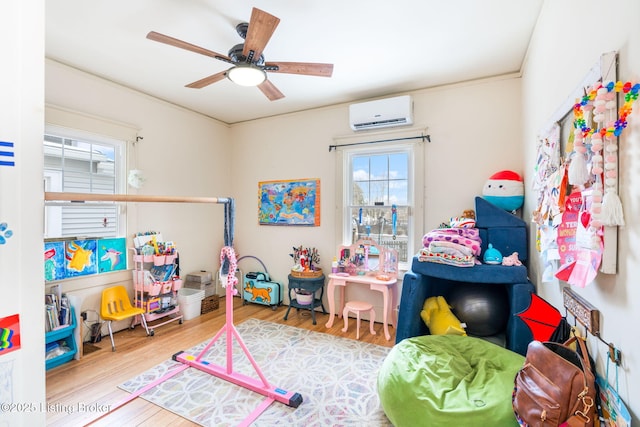 recreation room with a ceiling fan, wood finished floors, and a wall mounted AC