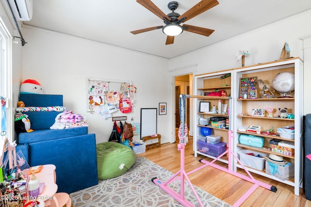 rec room featuring a wall mounted air conditioner, wood finished floors, and a ceiling fan