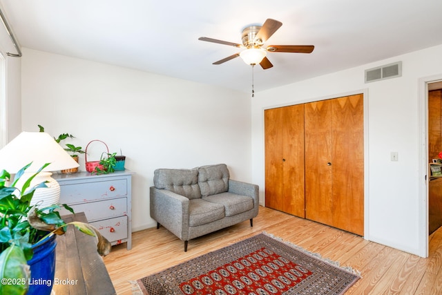 sitting room featuring baseboards, wood finished floors, visible vents, and a ceiling fan