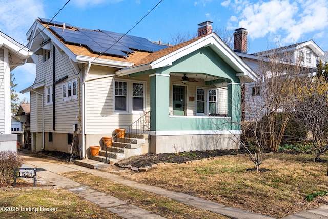 bungalow-style house featuring roof mounted solar panels, ceiling fan, and a chimney