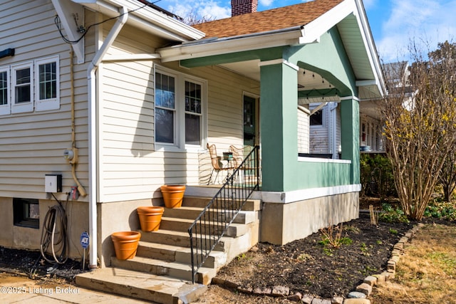 entrance to property featuring covered porch and a chimney