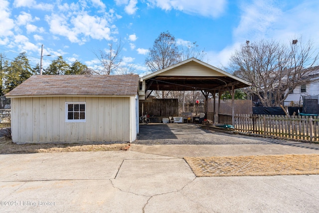 exterior space with driveway, fence, a carport, and roof with shingles