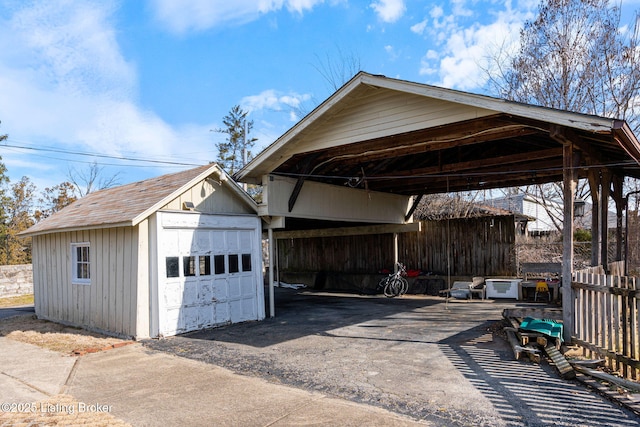 detached garage featuring aphalt driveway and a carport