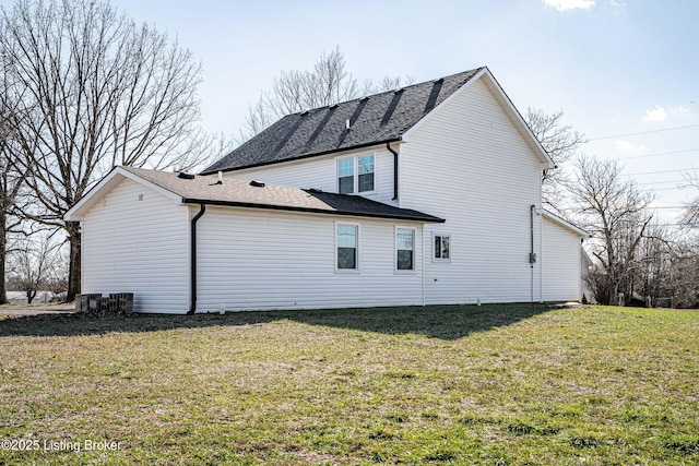 back of house with roof with shingles and a yard