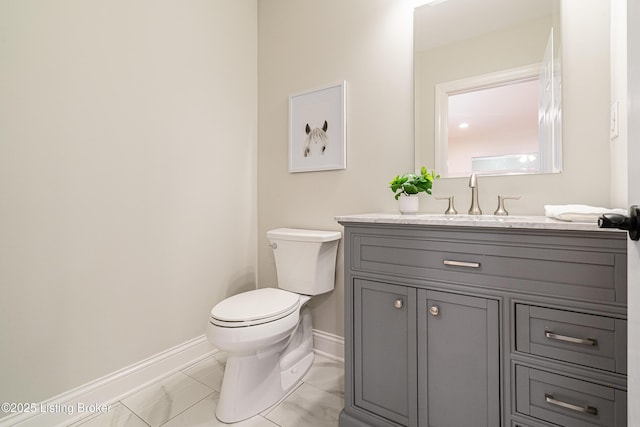 bathroom featuring marble finish floor, vanity, toilet, and baseboards