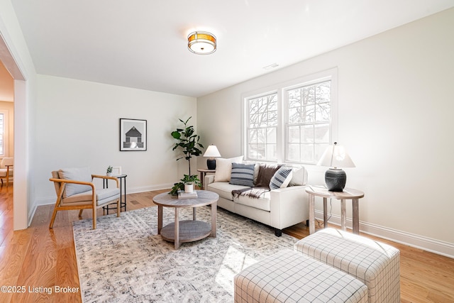 living room featuring wood finished floors, visible vents, and baseboards