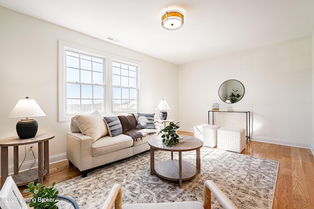 living area featuring light wood-type flooring, baseboards, and visible vents