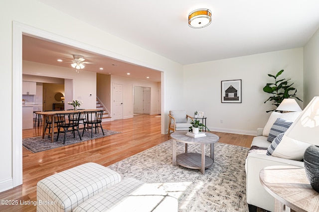 living area with ceiling fan, recessed lighting, baseboards, stairs, and light wood-type flooring