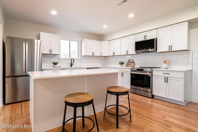 kitchen with light countertops, stainless steel appliances, a sink, and a kitchen breakfast bar