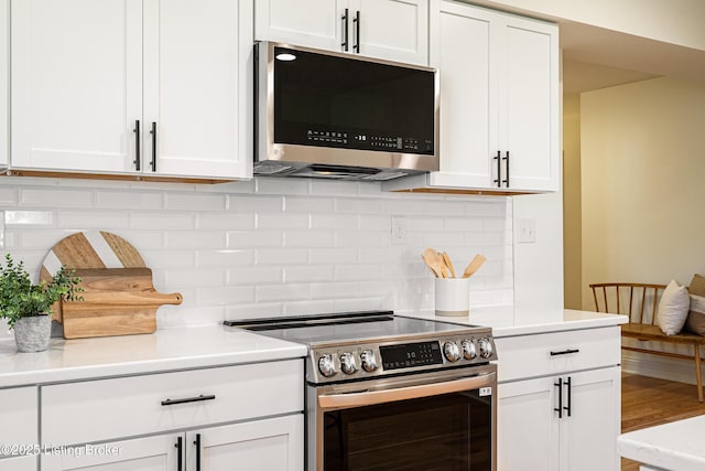 kitchen featuring tasteful backsplash, white cabinetry, stainless steel appliances, and light countertops