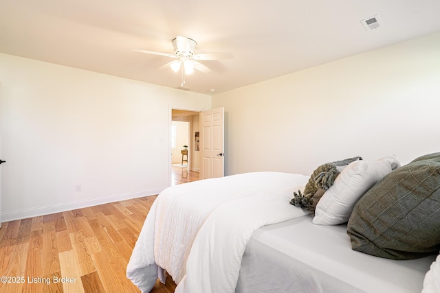 bedroom with ceiling fan, visible vents, light wood-style flooring, and baseboards