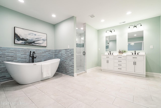 full bath featuring double vanity, a soaking tub, visible vents, a sink, and a shower stall