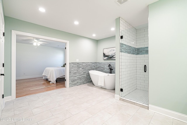 ensuite bathroom with visible vents, ceiling fan, a freestanding tub, a shower stall, and tile walls