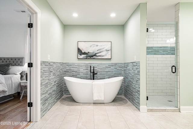 bathroom featuring tile walls, a freestanding bath, a shower stall, and ensuite bathroom