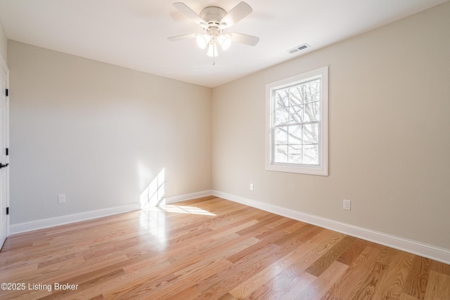 empty room featuring ceiling fan, light wood-style flooring, visible vents, and baseboards