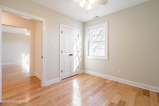 unfurnished bedroom featuring light wood-type flooring, baseboards, visible vents, and a closet