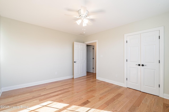 unfurnished bedroom featuring a ceiling fan, light wood-type flooring, a closet, and baseboards