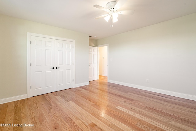 unfurnished bedroom with baseboards, ceiling fan, a closet, and light wood-style floors