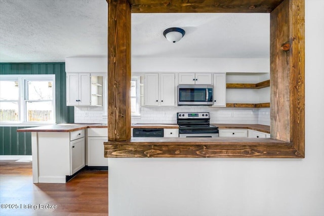 kitchen featuring open shelves, stainless steel appliances, tasteful backsplash, dark wood-type flooring, and a peninsula