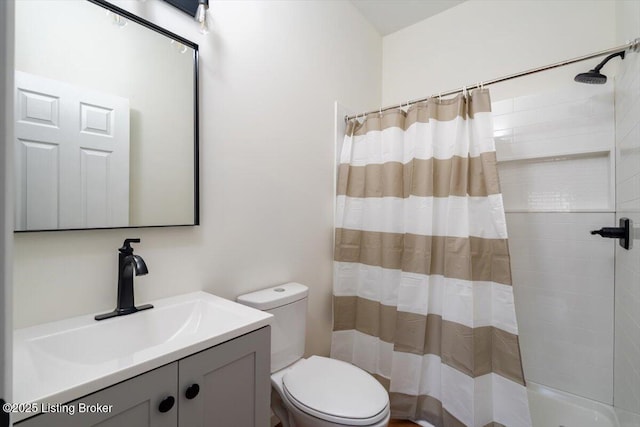 bathroom with curtained shower, vanity, and toilet