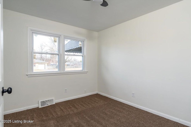 empty room featuring dark colored carpet, visible vents, and baseboards