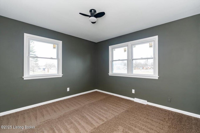 spare room with carpet, visible vents, and baseboards